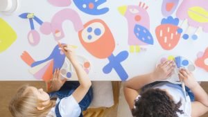 Deux enfants à une table travaillant sur des découpes de papier colorées avec des pinceaux.