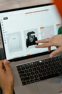 Gros plan de mains interagissant avec un site Web d'achat sur un écran d'ordinateur portable à l'intérieur.